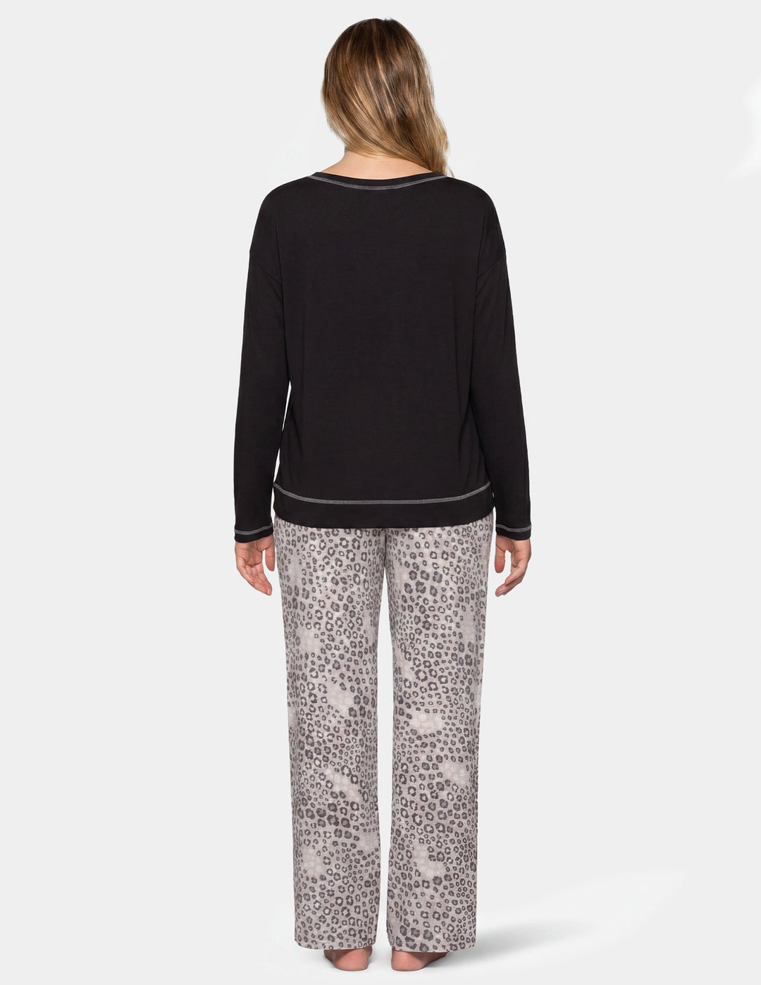 Back view of a woman wearing a black long sleeve pajama shirt and leopard print pajama pants.