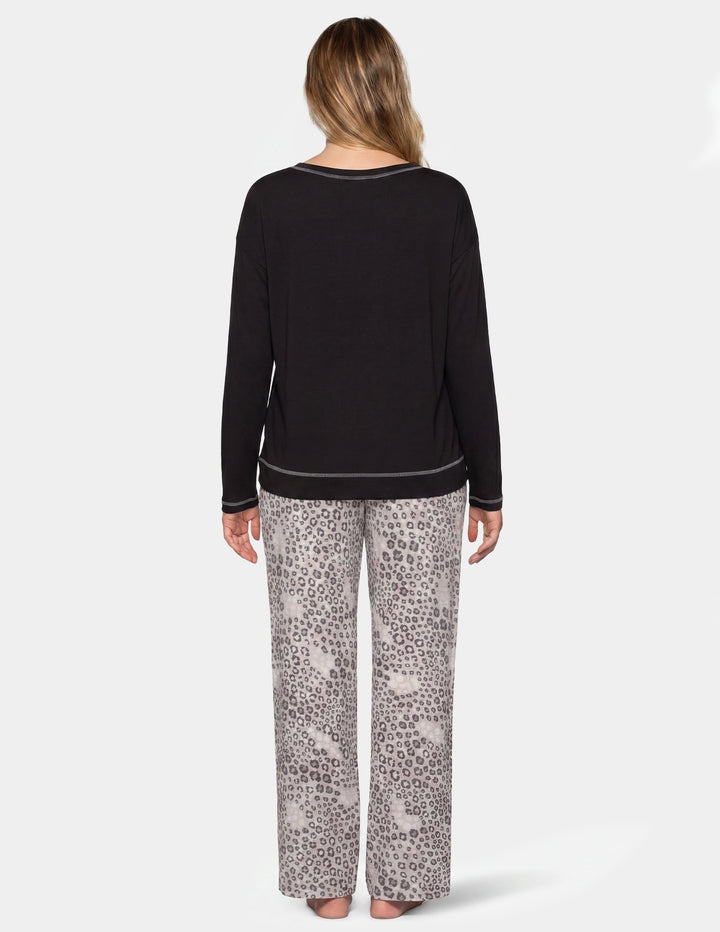 Back view of a woman wearing a black long sleeve pajama shirt and leopard print pajama pants.