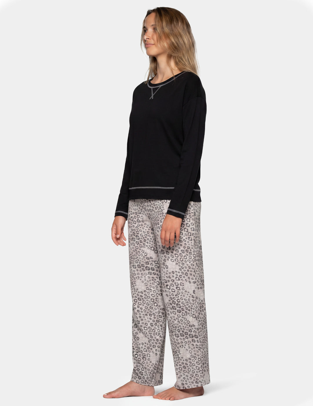Woman wearing a black long sleeve pajama shirt and leopard print pajama pants.