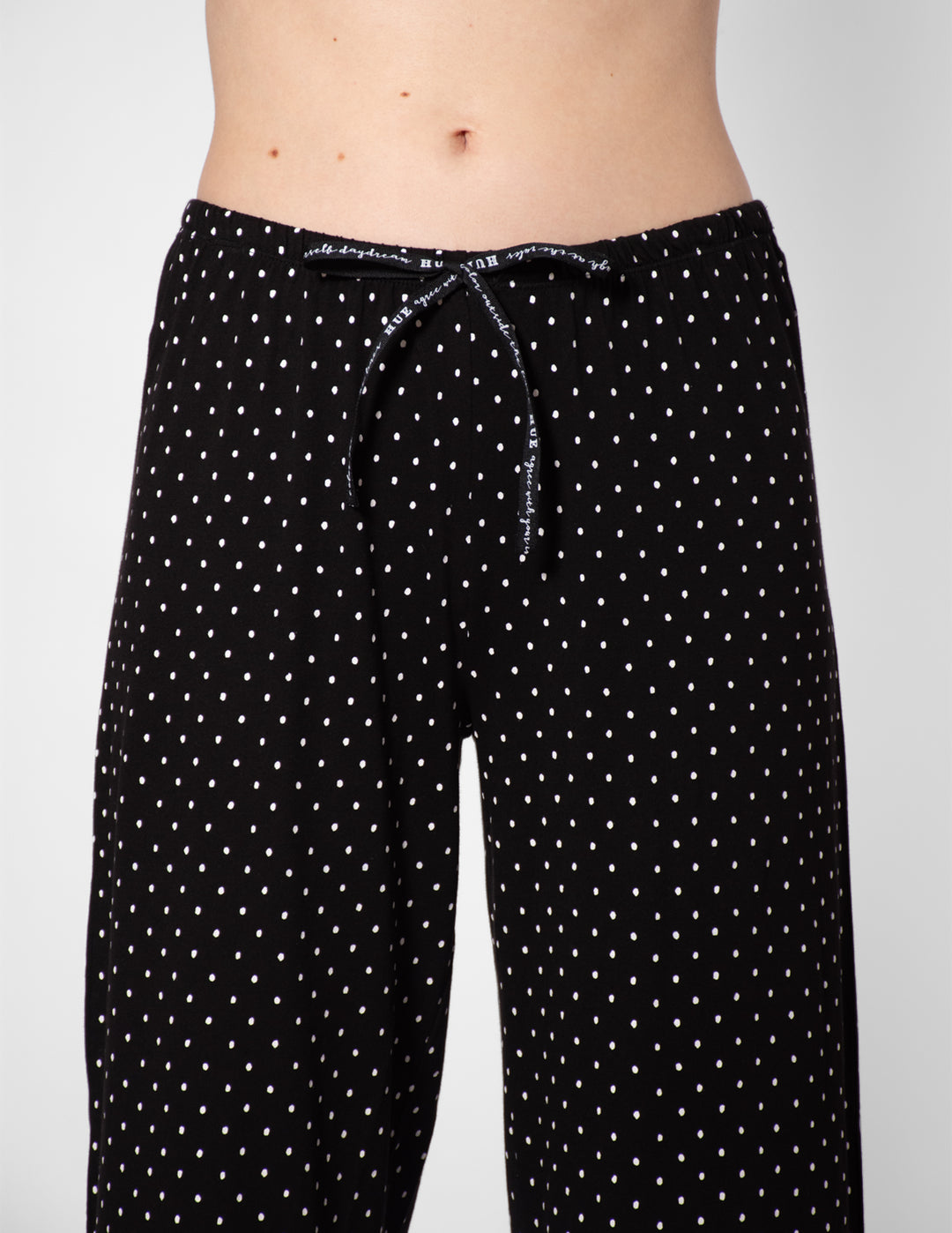 Black polka dot pajama pants on a plain background