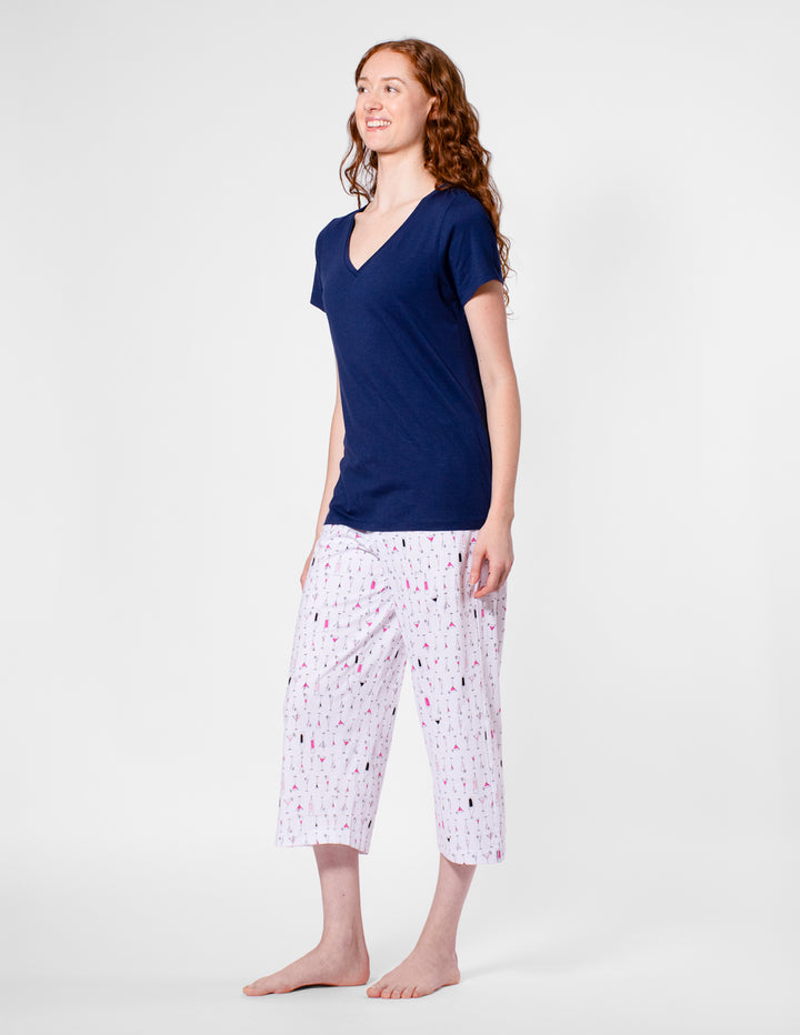 Woman wearing a navy blue top and patterned capri pants on a white background