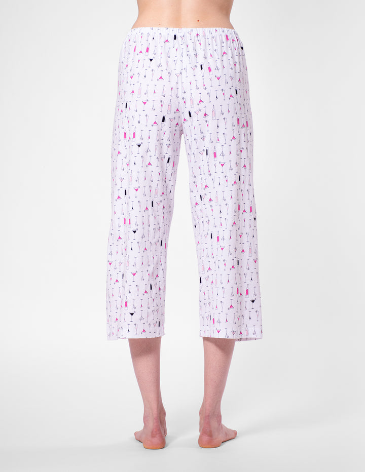 White capri pants with colorful pattern worn by a person on a white background