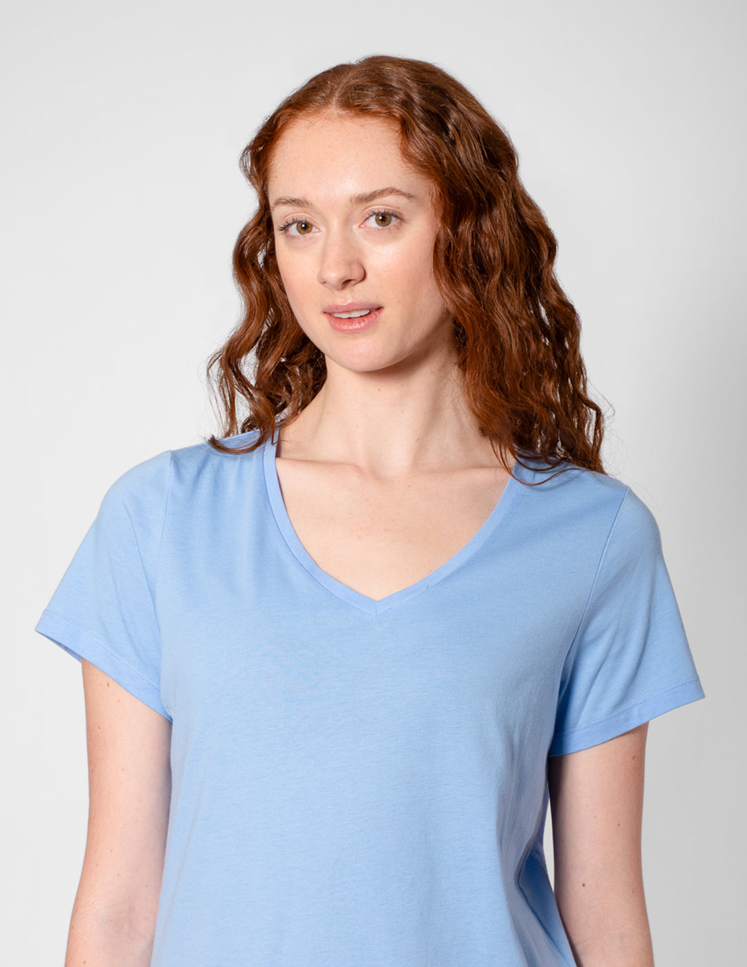 Woman wearing a light blue t-shirt against a plain background