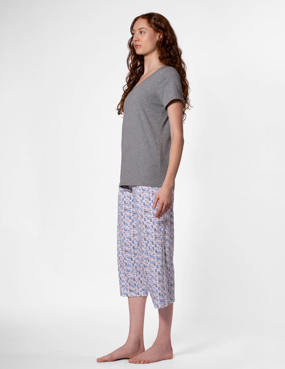 Woman wearing a gray t-shirt and patterned pajama pants on a white background