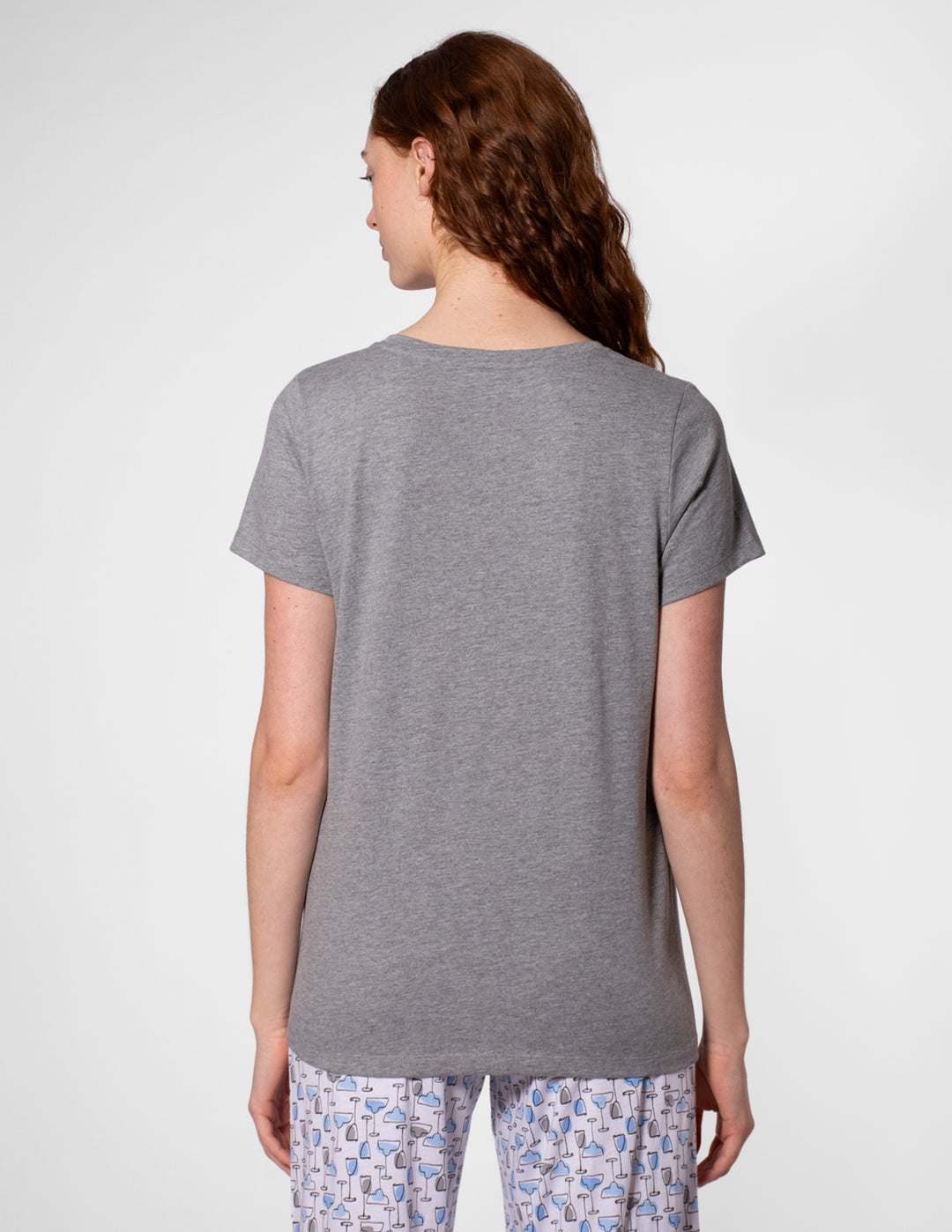 Person wearing a gray t-shirt and patterned pants on a white background