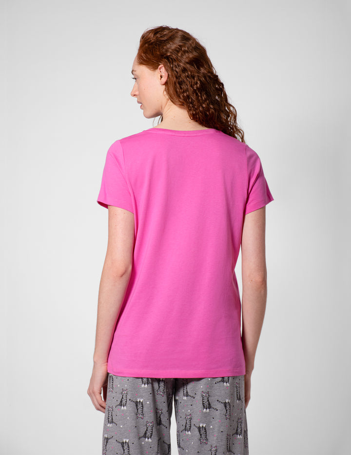 Person wearing a bright pink t-shirt and gray patterned pants on a white background