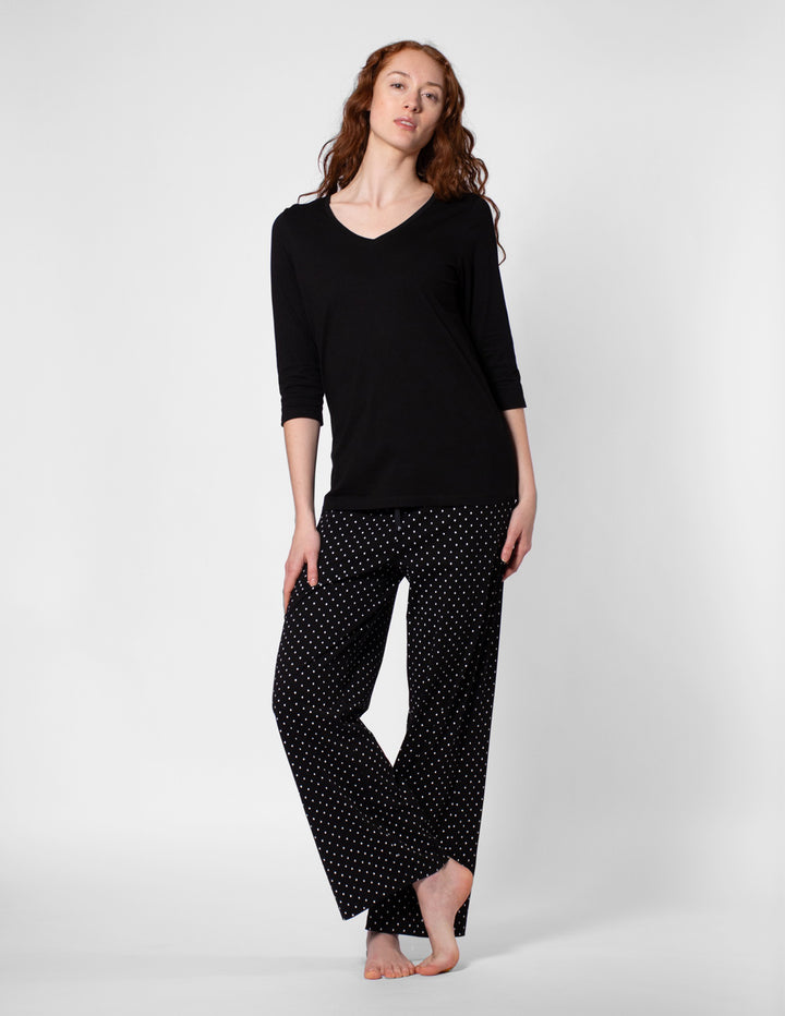 Woman wearing a black top and polka dot pants on a white background
