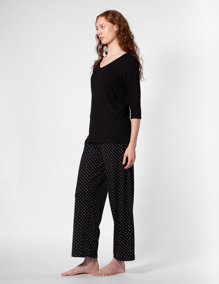 Woman wearing a black top and polka dot pants on a white background
