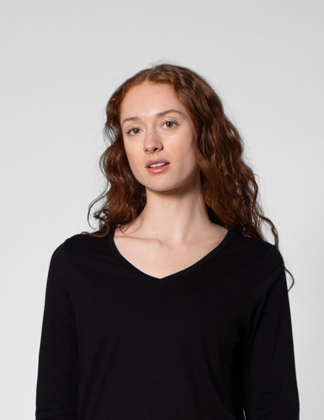 Woman wearing a black long-sleeve shirt against a plain background