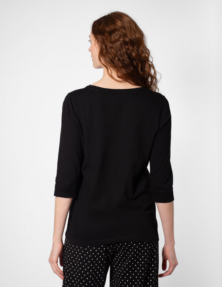 Woman wearing a black top with a plain background