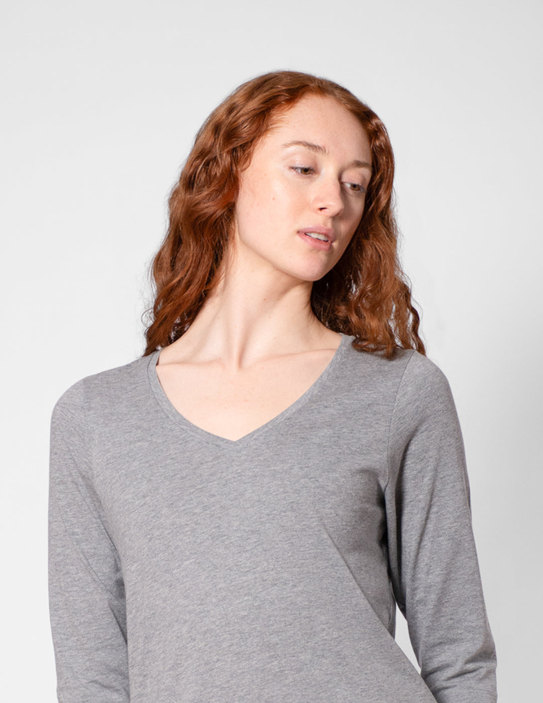 Woman wearing a gray long-sleeve shirt against a plain background