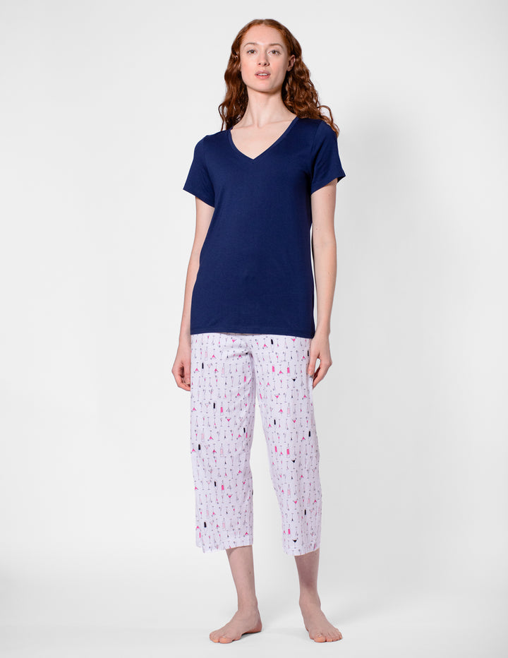 Woman wearing a navy blue top and white patterned pants on a white background