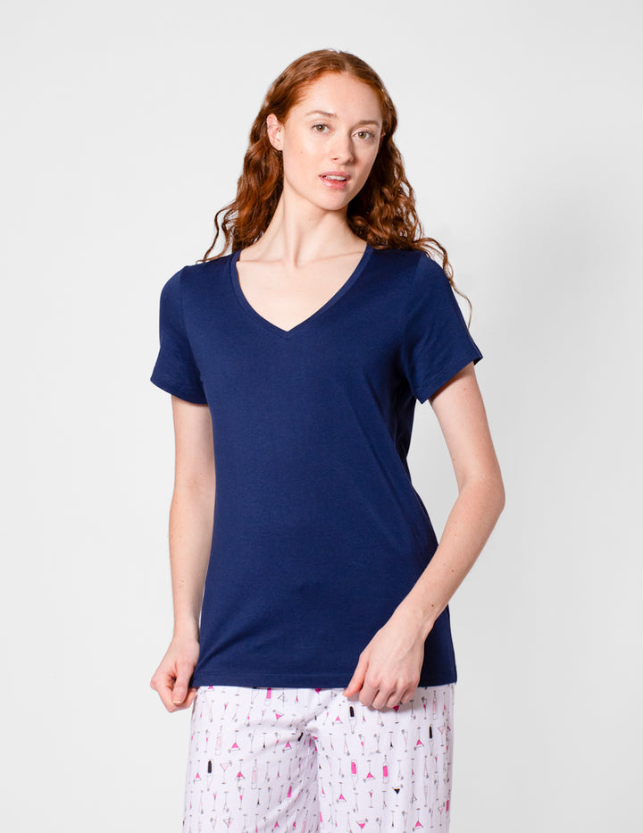 Woman wearing a navy blue t-shirt and patterned pants on a white background