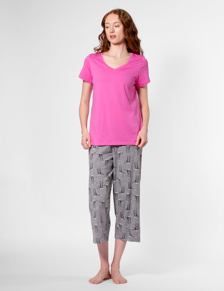 Woman wearing a pink top and gray patterned pants on a white background