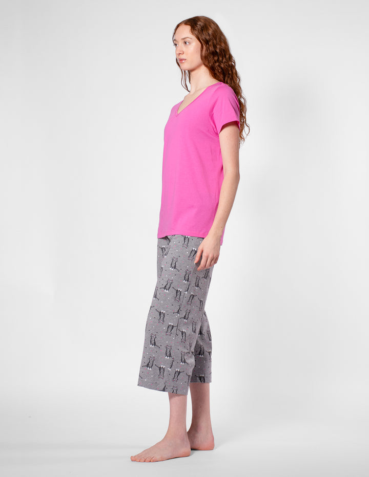 Woman wearing a pink top and gray patterned pants on a white background