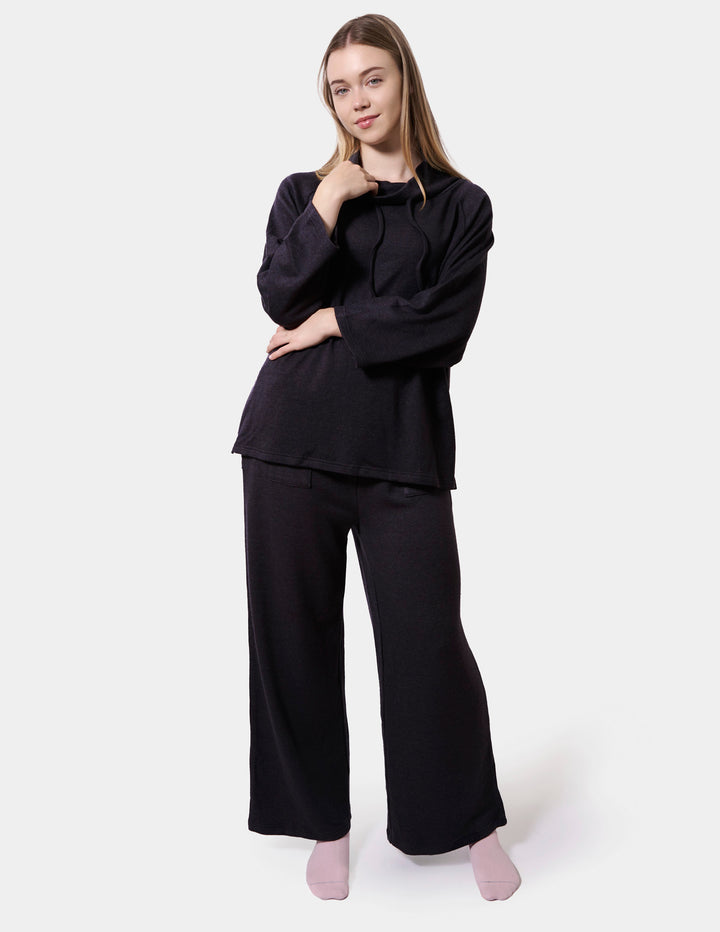 Woman wearing a dark grey lounge set on a white background