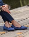 Denim jeans paired with Liflat shoes.  Model positioned in front of produce stand with oranges, mangoes and lemons.