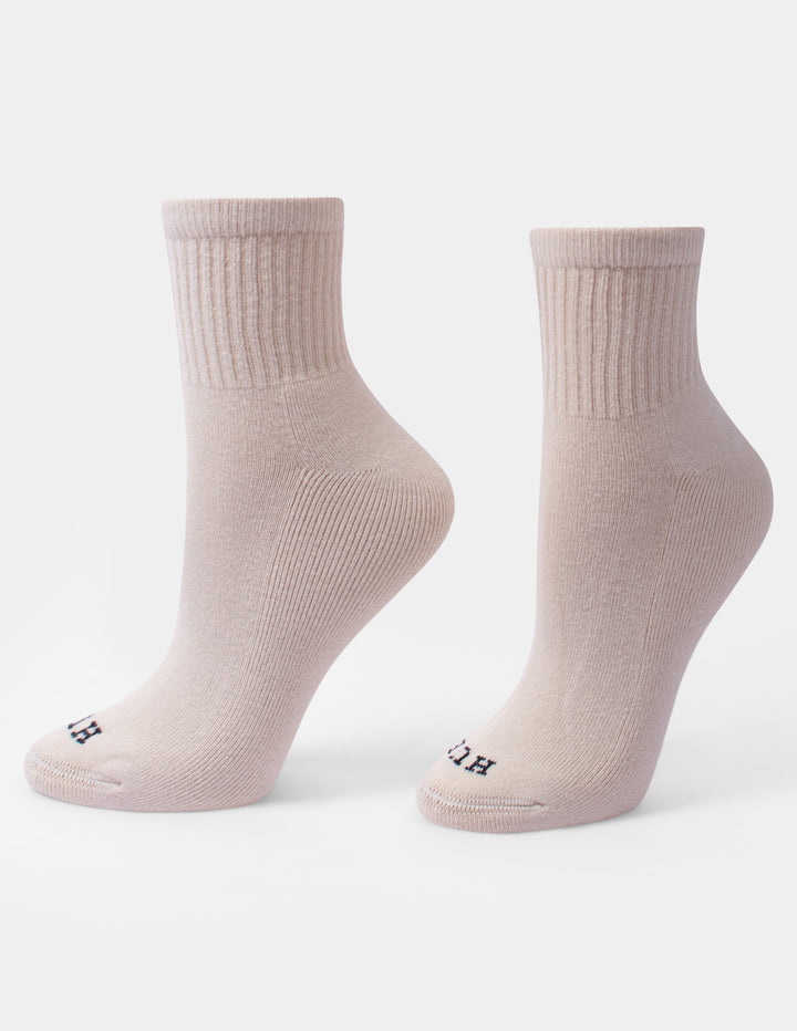 A pair of beige crew mini socks with a small HUE logo on the toes, displayed against a light gray background.