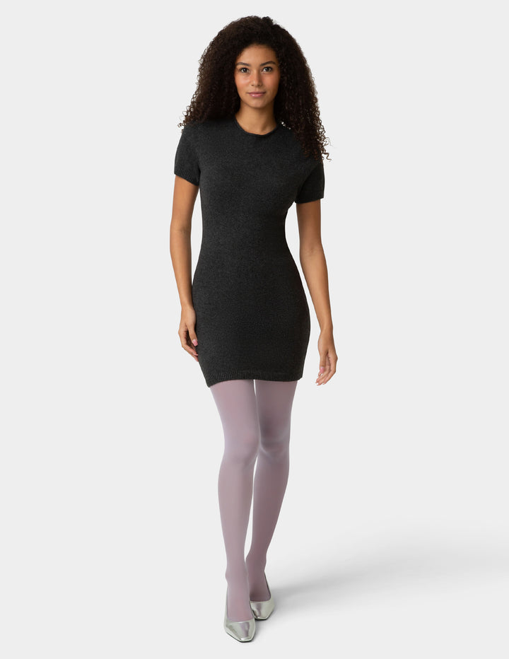 Woman wearing a black dress and purple tights on a white background