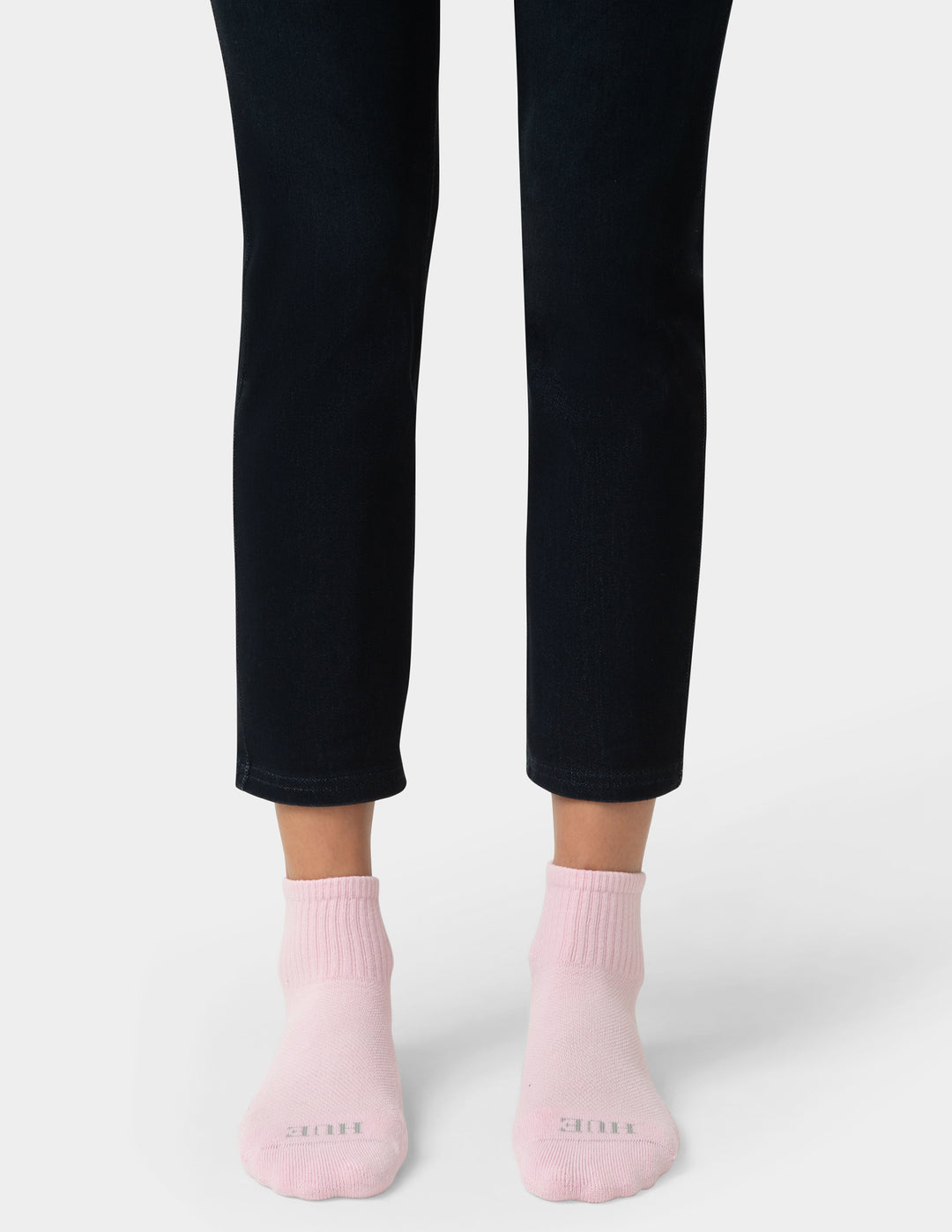 Person wearing black pants and pink socks on a white background