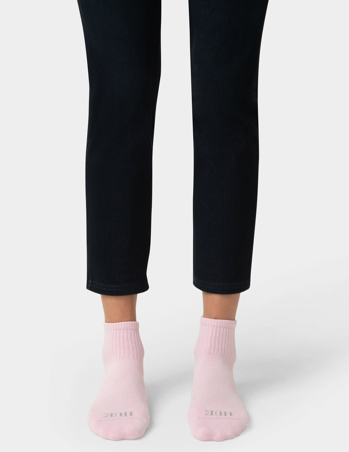 Person wearing black pants and pink socks on a white background