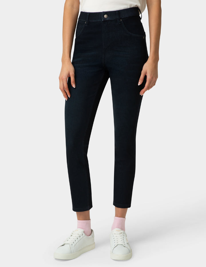 Person wearing dark blue jeans and white sneakers on a white background