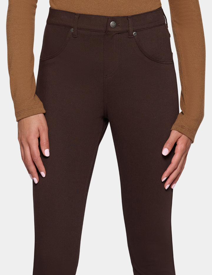 A close-up of a model wearing dark brown high-waisted leggings 