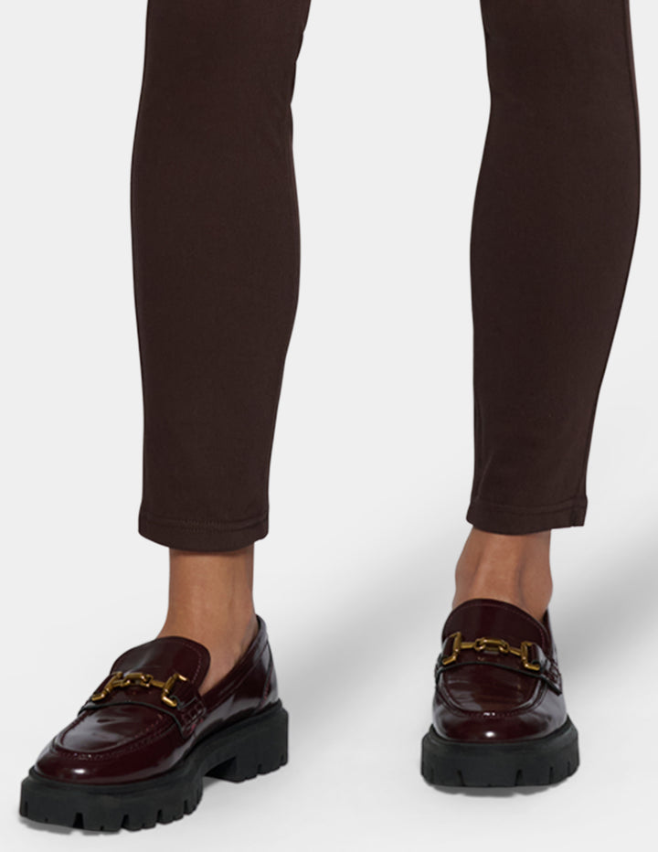 A close-up of a person's legs wearing dark brown leggings