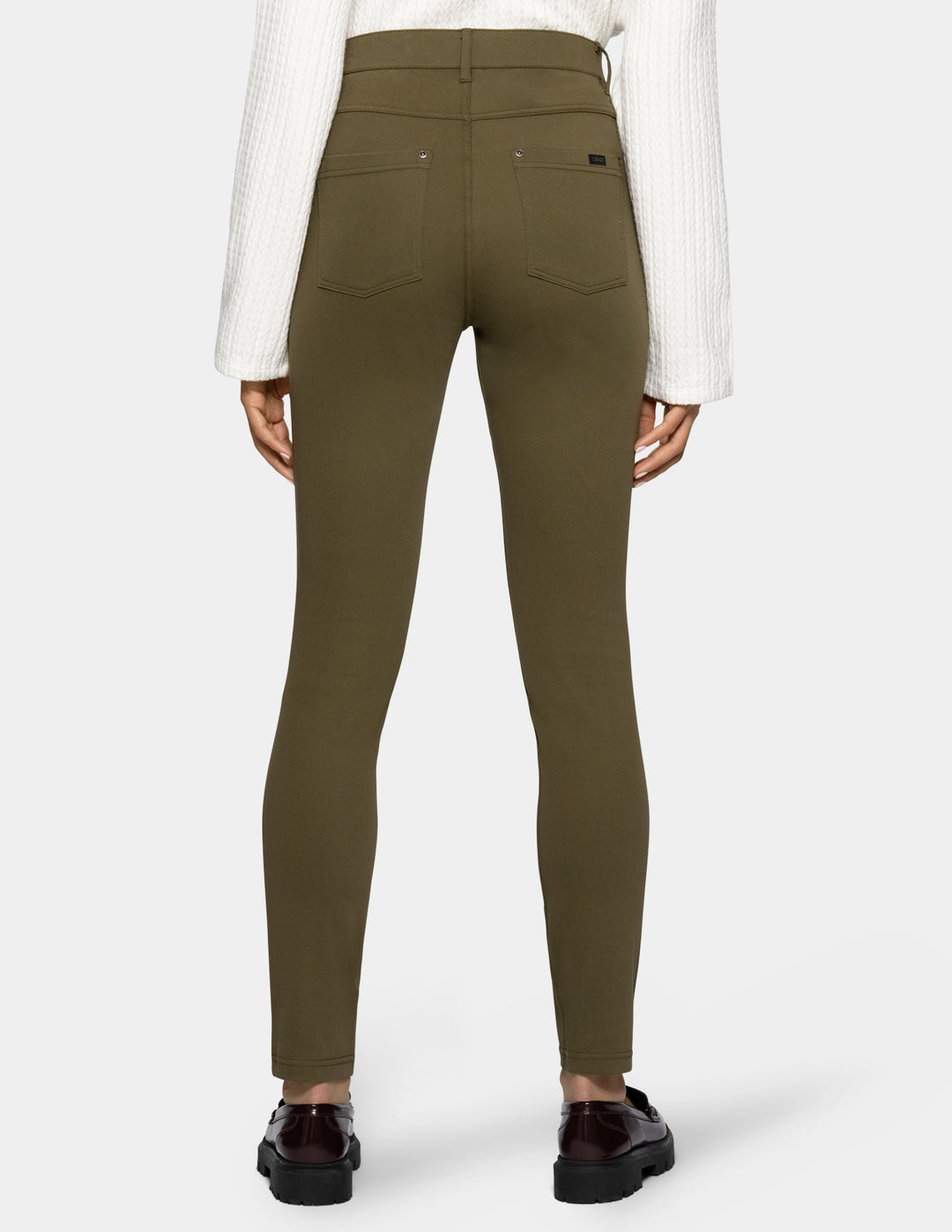 A person shown from the back wearing olive green leggings