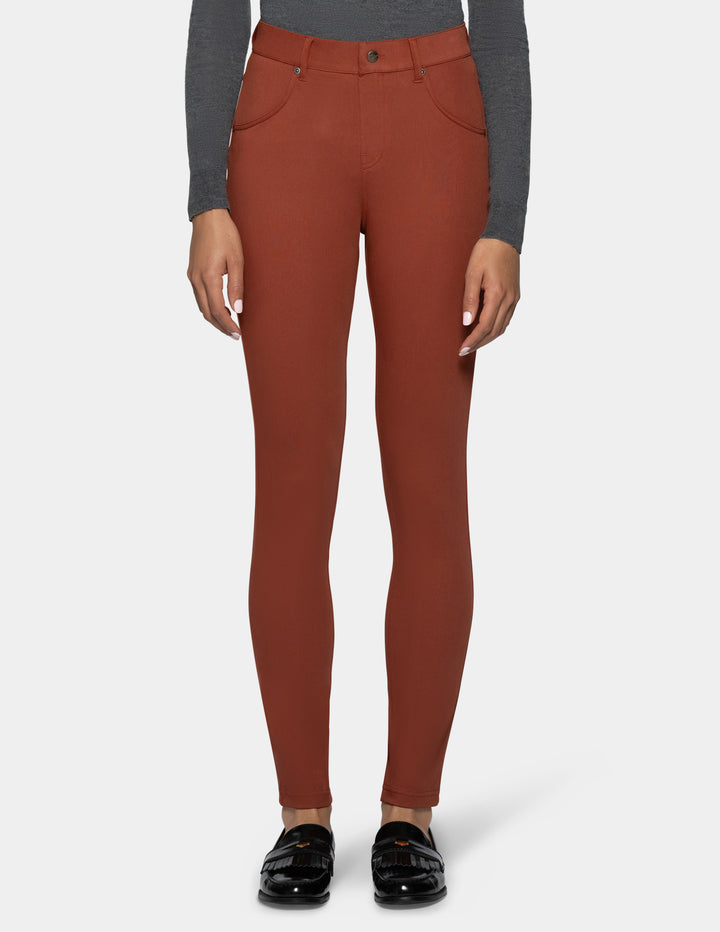 A model wearing a pair of rust-colored, high-waisted skinny leggings