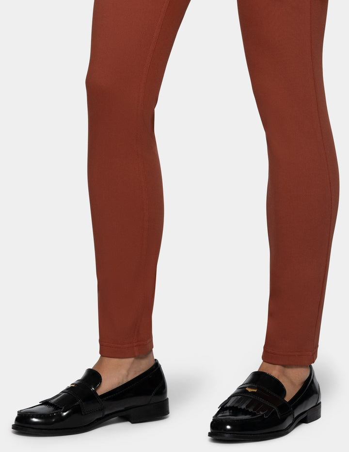 A close-up of a person's legs wearing rust-brown skinny leggings