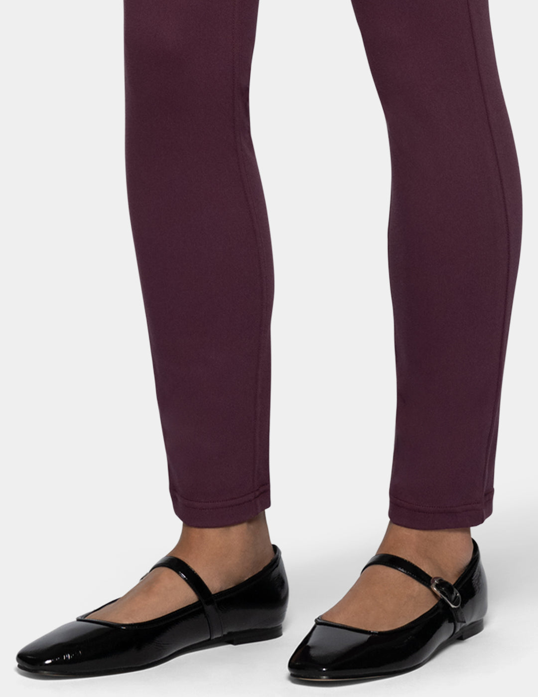 A close-up of a person's legs wearing dark plum leggings 