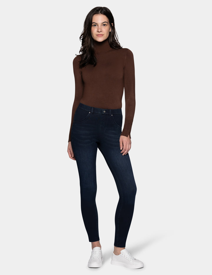 A model wearing dark blue leggings paired with a long sleeve brown top and sneakers.