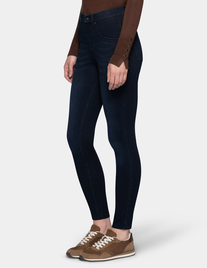 A model wearing dark blue leggings paired with a long sleeve brown top and sneakers.