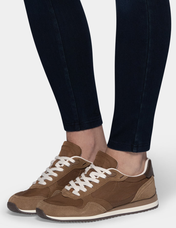 A model wearing dark blue leggings and sneakers.