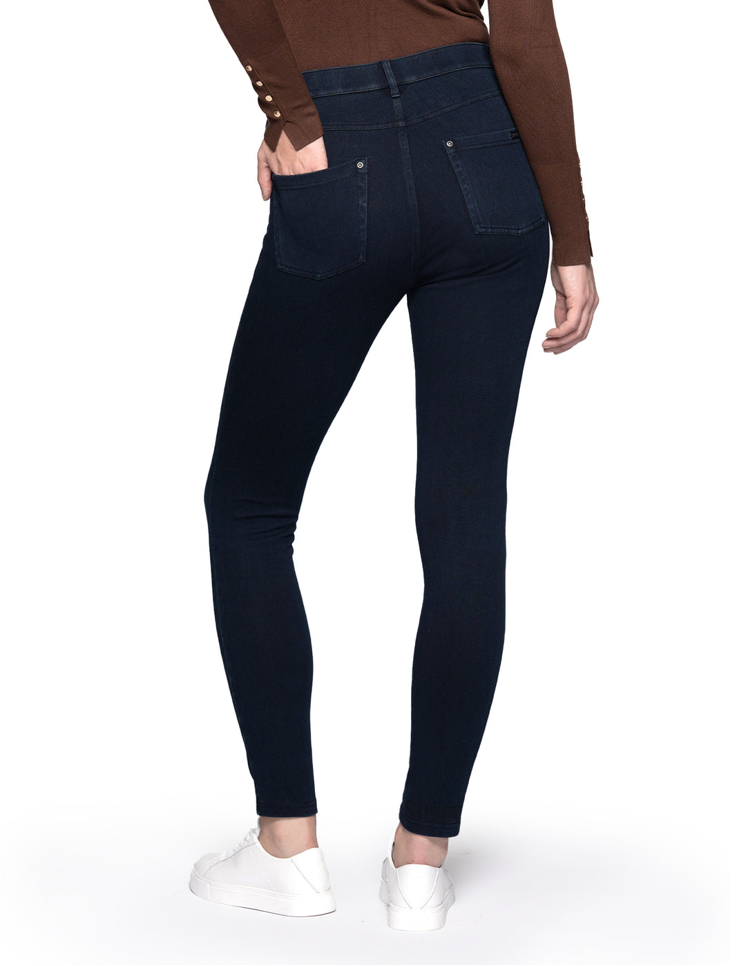 A model wearing dark blue leggings paired with a long sleeve brown top and sneakers.