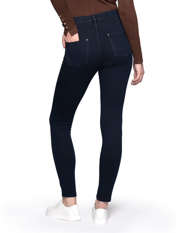 A model wearing dark blue leggings paired with a long sleeve brown top and sneakers.