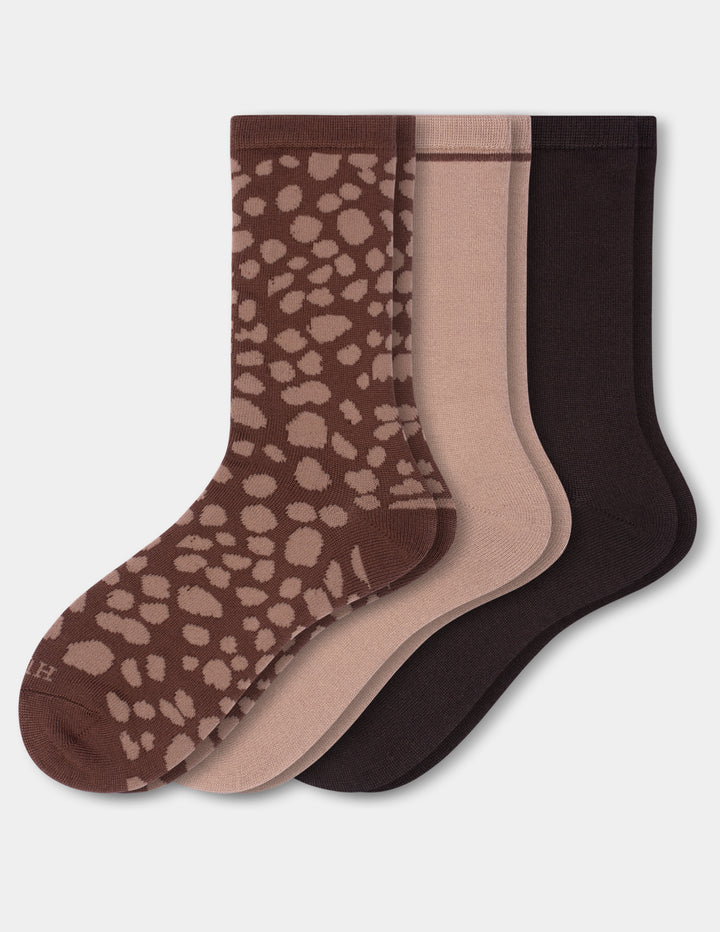Three pairs of neutral color crew socks on a light gray background. 