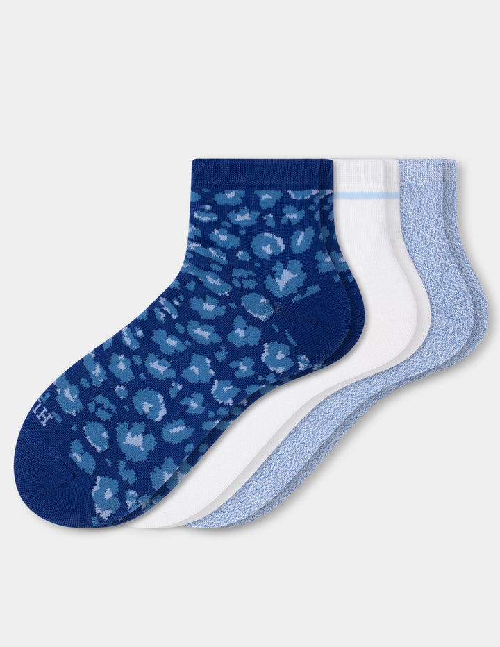 Three pairs of ankle socks arranged overlapping on a light gray background: one dark blue with a lighter blue leopard print, one white with a thin light blue stripe, and one light blue textured pair.