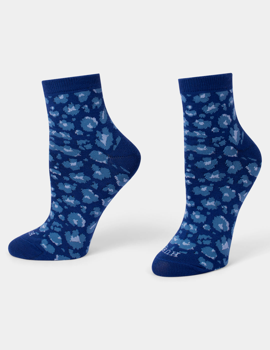A pair of navy blue crew socks with a light blue and white leopard pattern, displayed on a clean light gray background.