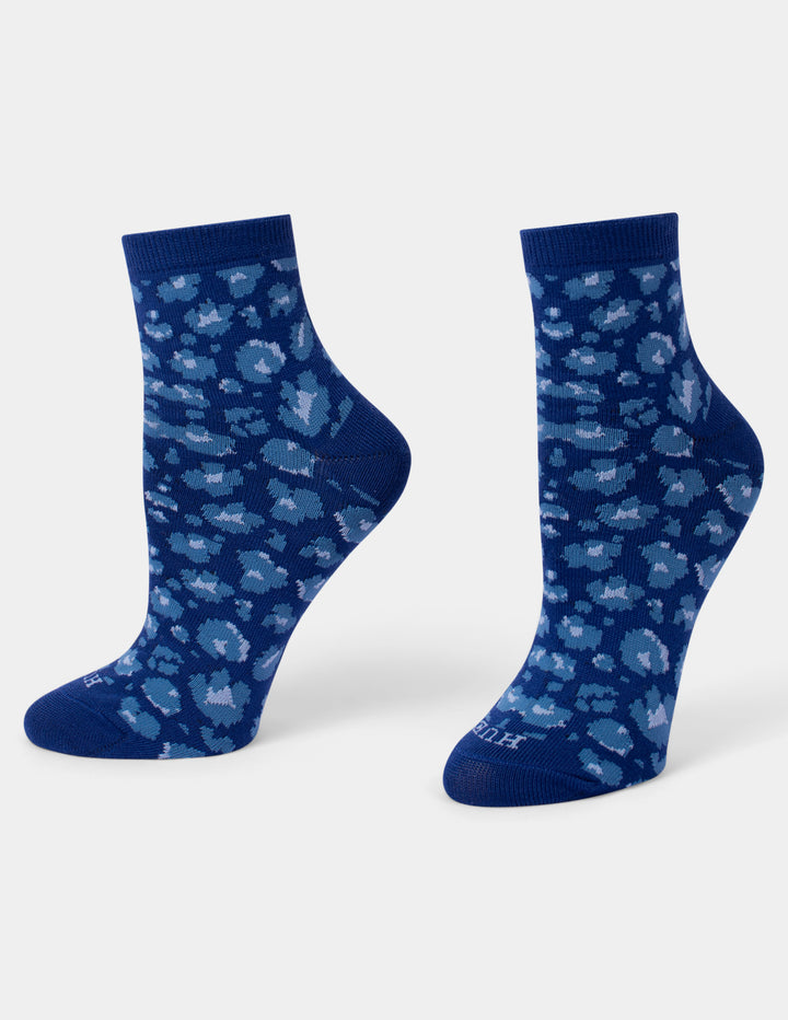 A pair of navy blue crew socks with a light blue and white leopard pattern, displayed on a clean light gray background.