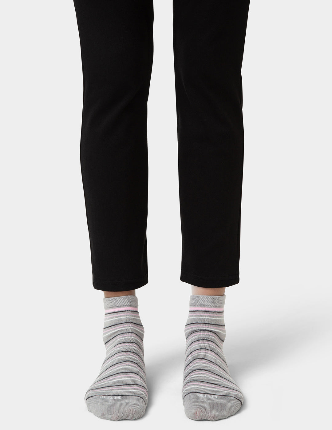 Person wearing black pants and gray striped socks on a white background