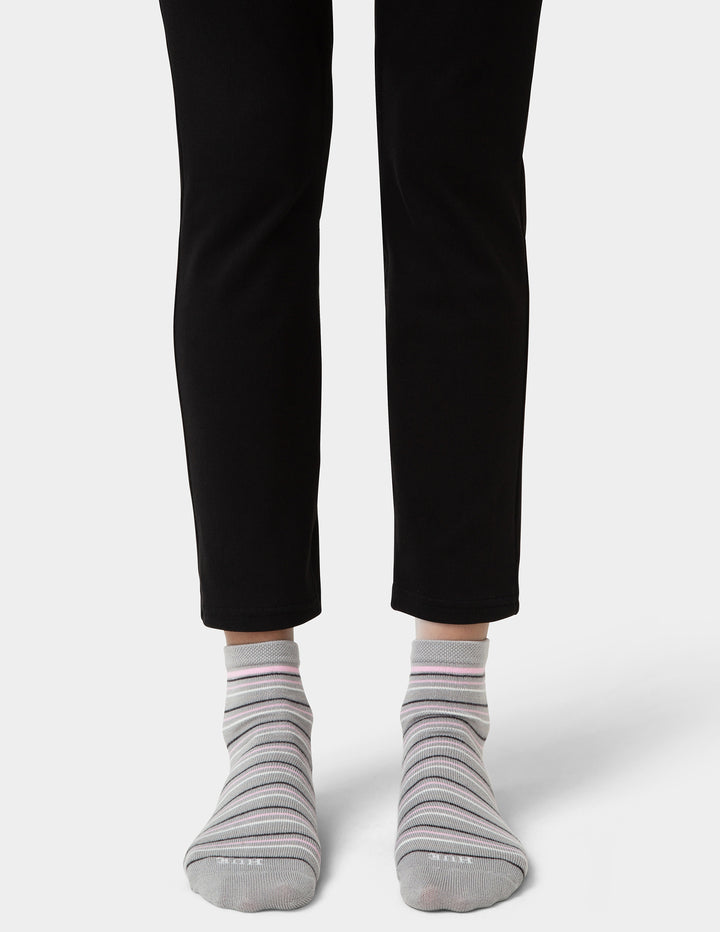 Person wearing black pants and gray striped socks on a white background