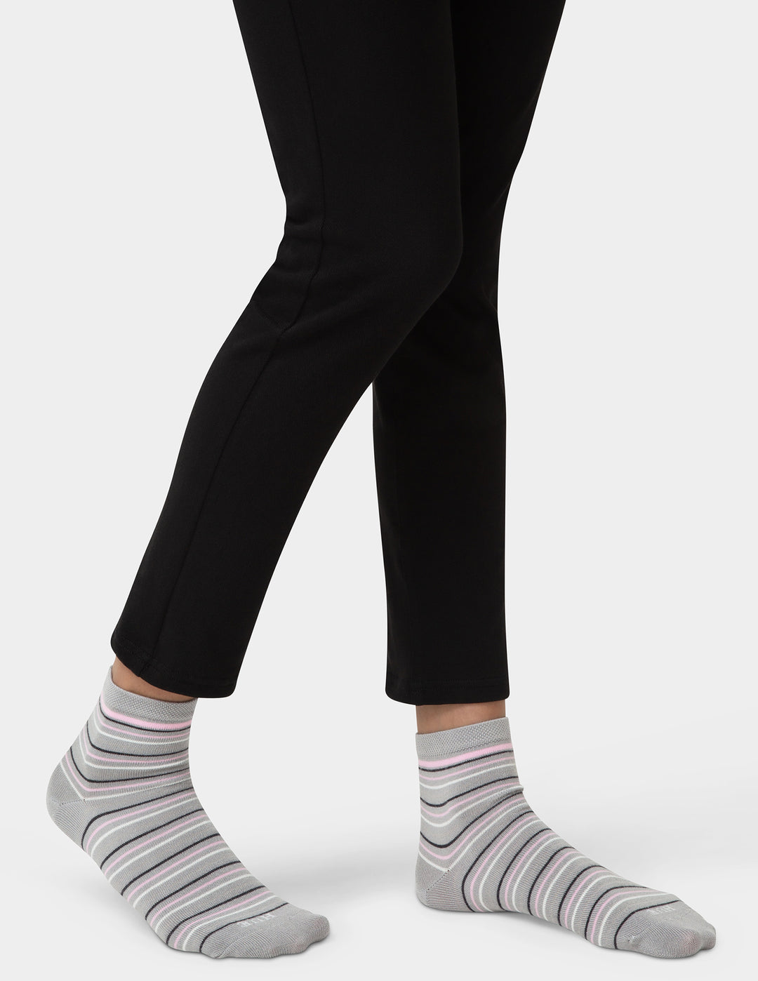Person wearing black pants and gray striped socks on a white background