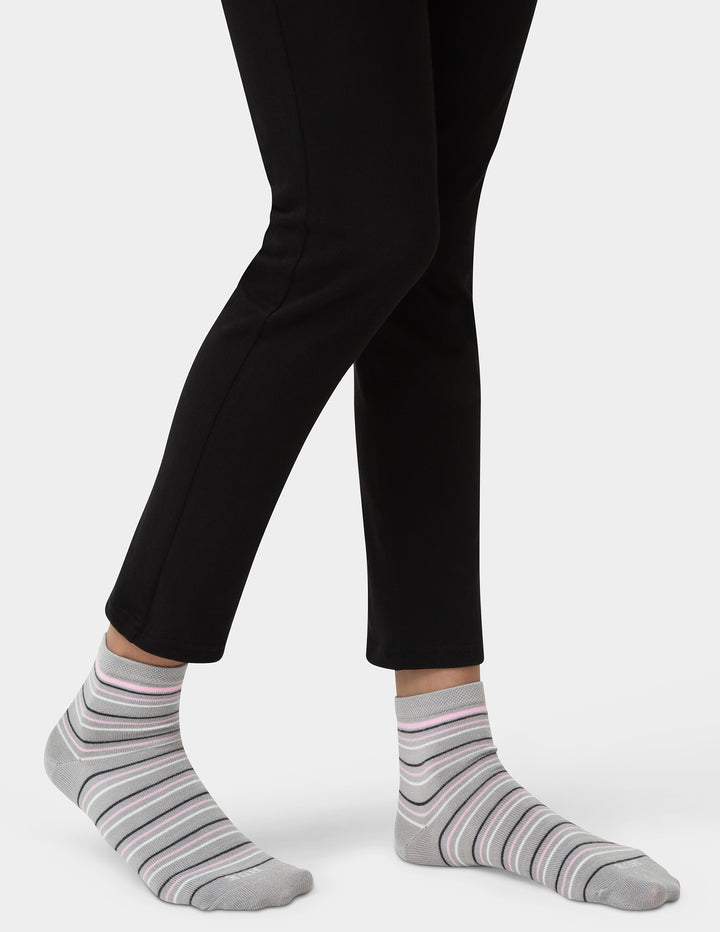 Person wearing black pants and gray striped socks on a white background