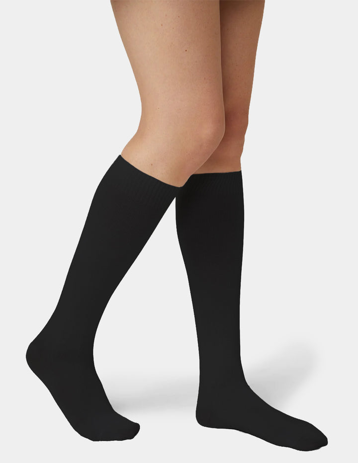 A model wearing black knee high socks photographed against a light gray background.