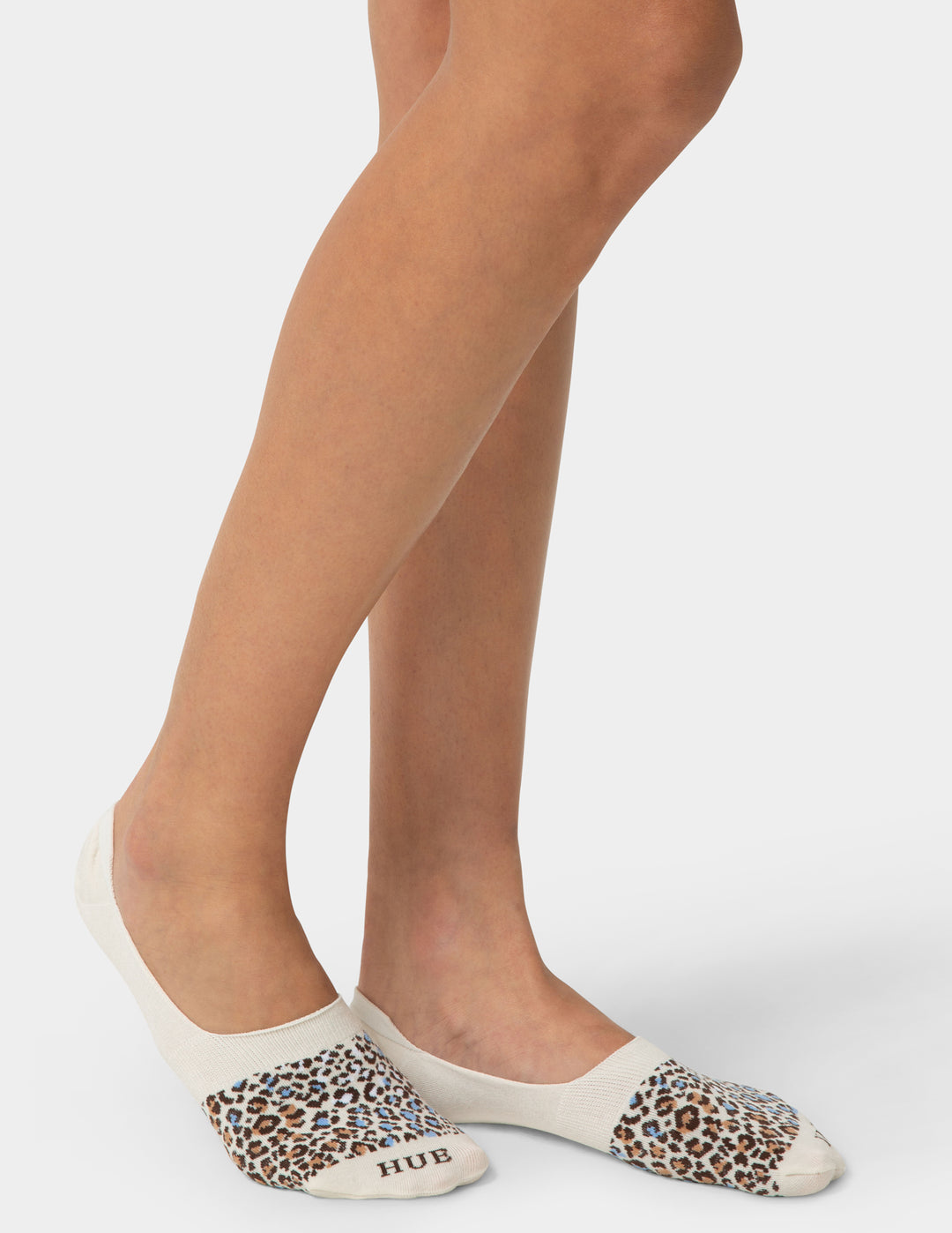 Leopard print socks with white toes and heels worn by a person on a light gray background