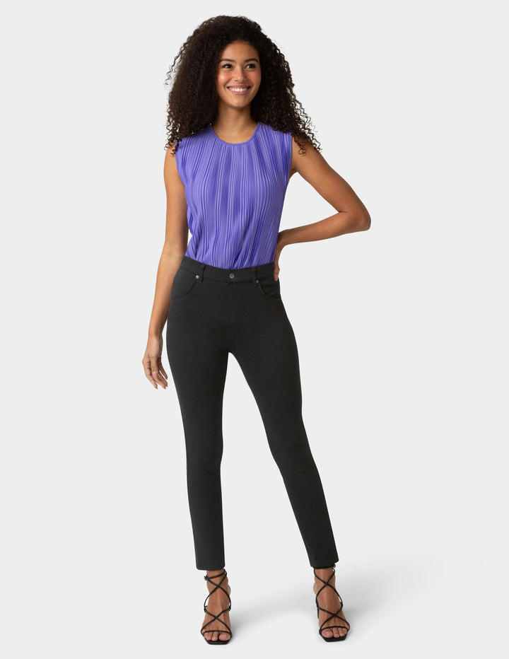 Woman wearing a purple sleeveless top and black pants on a white background
