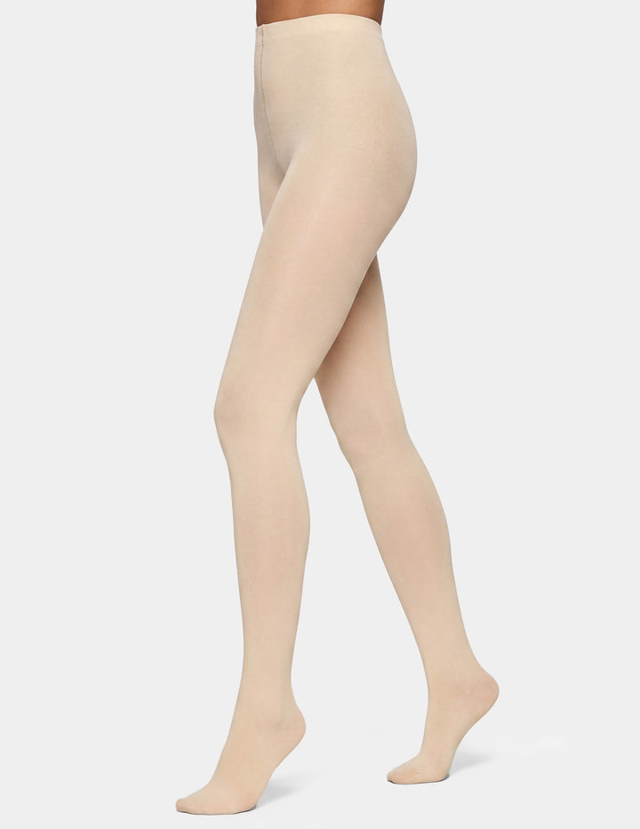 A model's legs wearing sheer, skin-toned tights against a light gray studio background.
