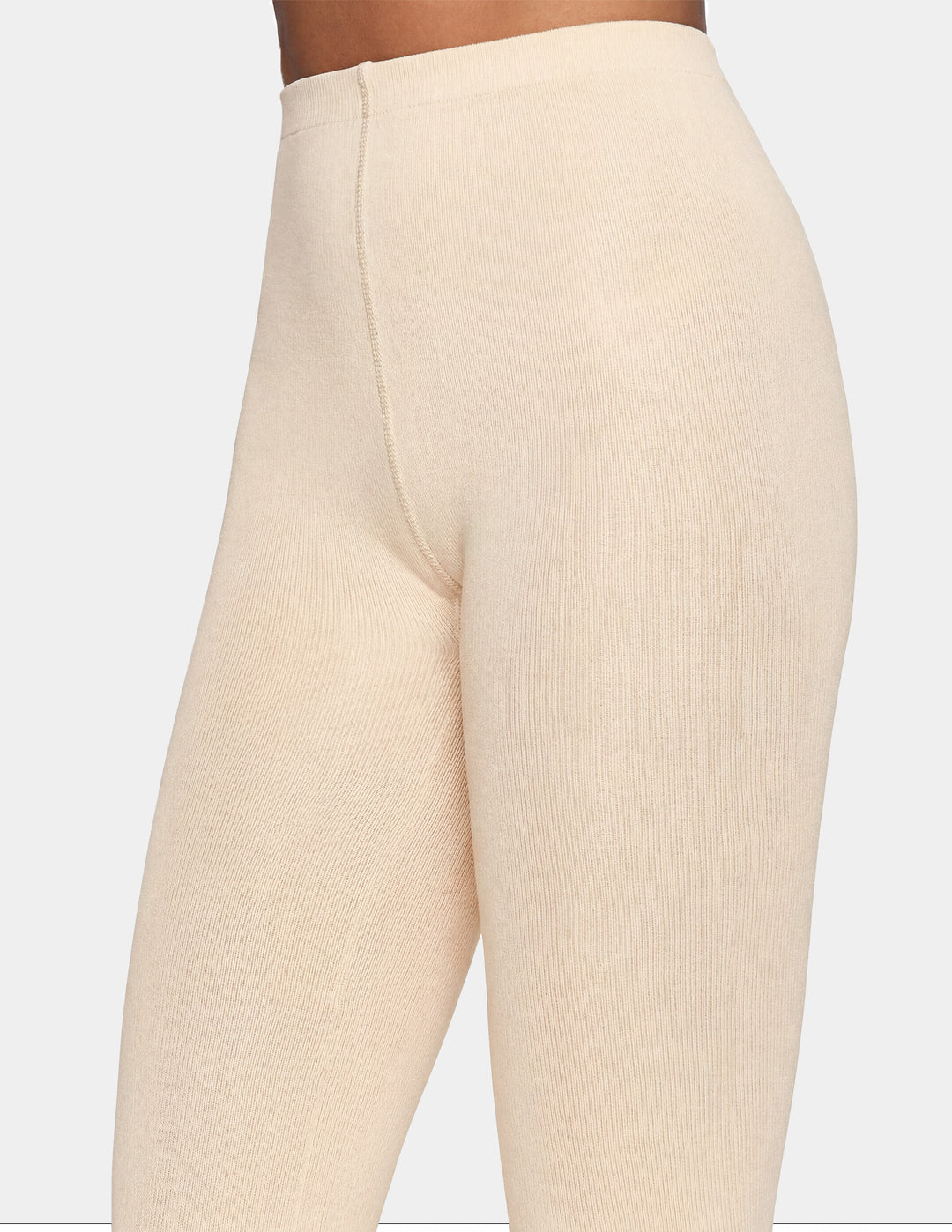 Close-up of a person wearing ribbed knit leggings in a light cream or off-white shade, shown from the waist down against a plain light gray background.
